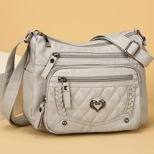 Sac à bandoulière tendance pour femme Un modèle uni et polyvalent, rehaussé d'un charmant détail en forme de cœur. Doté de multiples poches pratiques et d'une bandoulière facilement ajustable.