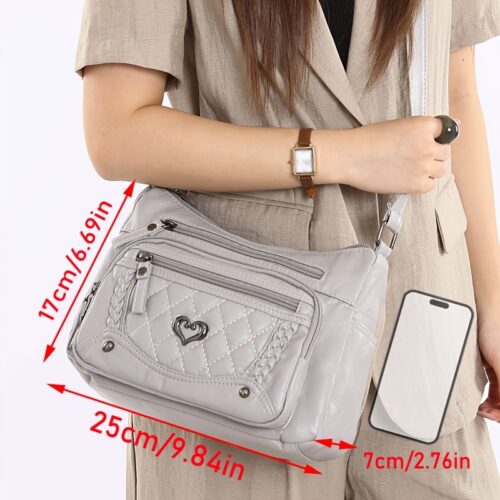 Sac à bandoulière tendance pour femme Un modèle uni et polyvalent, rehaussé d'un charmant détail en forme de cœur. Doté de multiples poches pratiques et d'une bandoulière facilement ajustable.